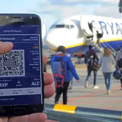 Telefon z kartą pokładową Ryanair i samolot na tle.