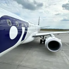 Samolot LOT-u z dużym logo na kadłubie na płycie lotniska.