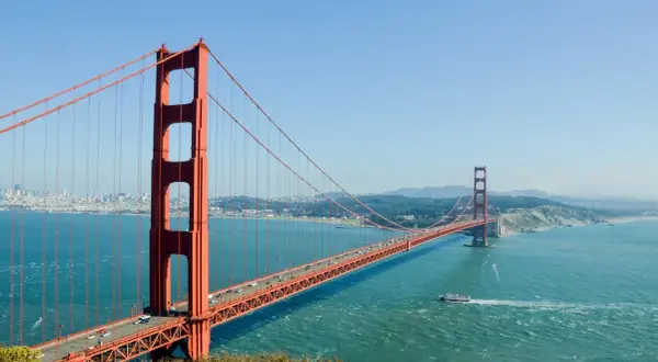 Most znany na świecie, Golden Gate Bridge w San Francisco, z ruchem samochodowym i łodzią na wodzie.