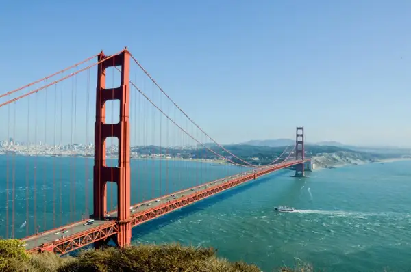 Most znany na świecie, Golden Gate Bridge w San Francisco, z ruchem samochodowym i łodzią na wodzie.